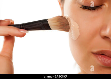 Una giovane donna di liquido applicato foundation sul suo viso con una spazzola Foto Stock