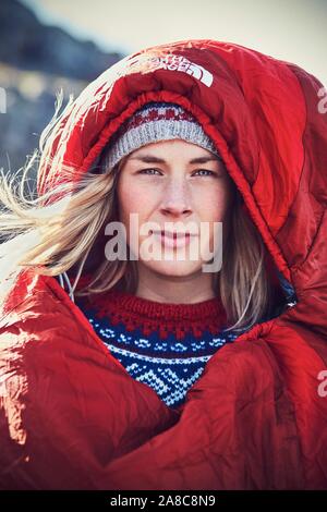 Ritratto di una giovane donna in un rosso sacco a pelo guardando nella telecamera, natura, lo stile di vita di campeggio, outdoor lifestyle, Prekestolen, Rogaland, Norvegia Foto Stock