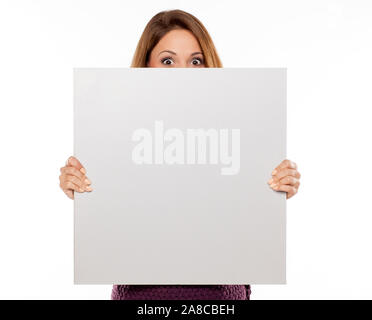 Giovane bella donna spiata dietro blank board per la pubblicità Foto Stock