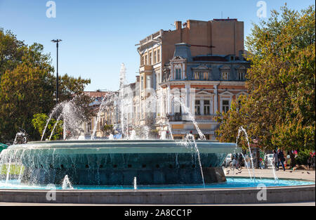 Ruse, Bulgaria - 29 Settembre 2014: Street view con fontana al giorno d'estate, la gente comune a piedi la strada Foto Stock