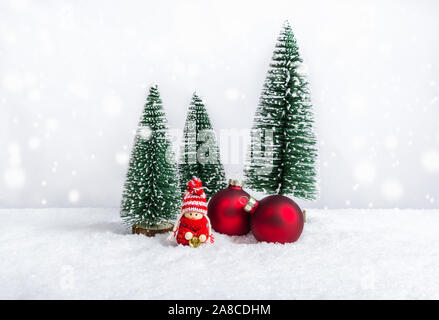 Bambola di natale come piccolo bambino in maglia maglione rosso holding campana vicino a Natale e baubles di abeti. Natale figure come handmade holiday composizioni Foto Stock