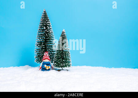 Carino piccolo giocattolo bambino in maglia blu maglione holding campana. Carino il Natale figura come una vacanza fatta a mano decorazione contro sfondo blu con copy-sp Foto Stock