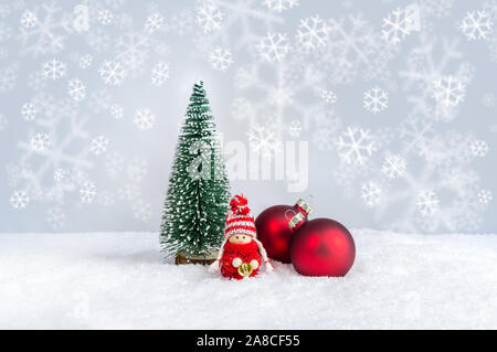 Natale bambino figura in rosso maglione campana di contenimento in prossimità di abete e ornamenti. Carino bambola di Natale come una vacanza fatta a mano contro di decorazione F Foto Stock