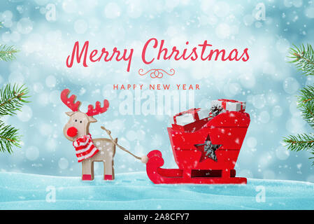 Buon Natale biglietto di auguri con il giocattolo carino delle sue renne con la slitta piena di regali in neve. Foto Stock