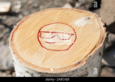 Faccina sorridente con vetri verniciati in rosso. Illustrazione di emoticon dipinta su un log. Il pensiero positivo i concetti. Foto Stock