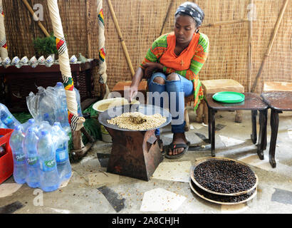 Una giovane donna etiope la tostatura i chicchi di caffè in preparazione del tradizionale caffè etiope. Foto Stock