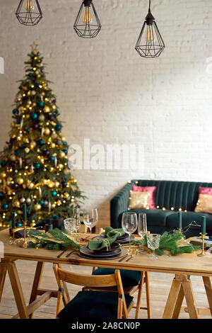 Serata di Natale a lume di candela. appartamenti classic con un caminetto bianco, decorate albero, divano letto, grandi finestre e un lampadario Foto Stock