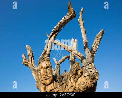 Matala, Heraklion, Creta, Grecia. Antico tronco di albero scolpito nella forma di volti umani da artista cretese Spyros Stefanakis. Foto Stock
