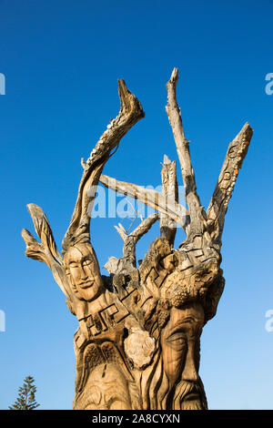 Matala, Heraklion, Creta, Grecia. Antico tronco di albero scolpito nella forma di volti umani da artista cretese Spyros Stefanakis. Foto Stock