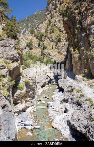 Agia Roumeli, Parco Nazionale Samaria, la Canea, Creta, Grecia. Escursionista che attraversa il ponte pedonale sul fiume nella gola di Samaria. Foto Stock