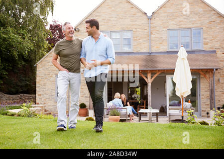 Senior padre e figlio adulto camminare e parlare in giardino insieme Foto Stock