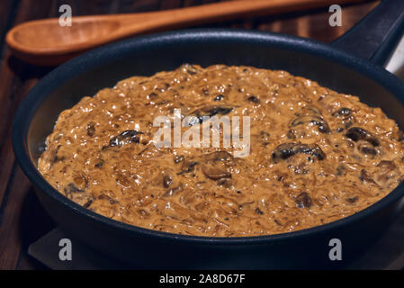 Padella calda con una deliziosa casa cremosa salsa fatta con saltata di funghi champignon, cipolle, olio extra vergine d'oliva, la salsa di soia e spezie. Foto Stock