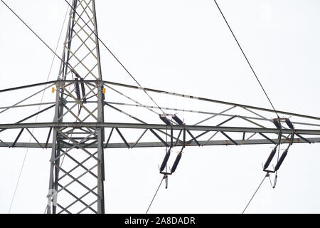 Dettaglio di alta tensione e linee elettriche ad alta tensione pilone contro il cielo grigio. Visto in Franconia / Baviera in Germania nel mese di novembre. Foto Stock