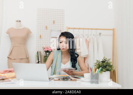 Giovane e bella Asian business woman/stilista di moda utilizzando computer in officina Foto Stock