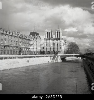 Degli anni Cinquanta, storico vista dal Pont au Double attraverso il Fiume Senna per la cattedrale di Notre Dame di Parigi, Francia. Un medievale chiesa cattolica sull'Ile de la Cite nel 4 ° arrondissement di Parigi, è considerato uno dei migliori esempi di architettura gotica francese. Foto Stock