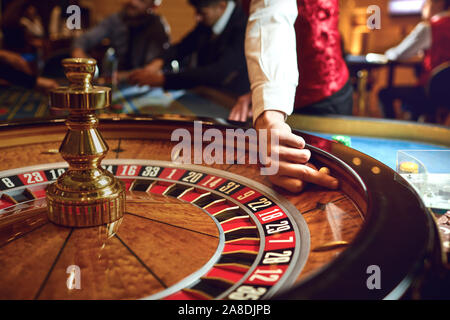 Mano di un croupier su una roulette whell in un casinò. Foto Stock