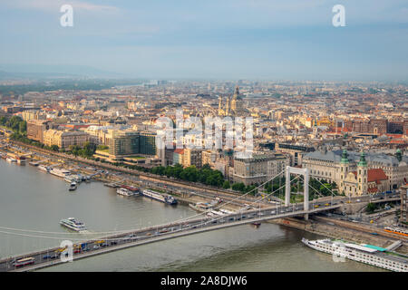 Una vista panoramica dalla collina di Gellert sulla città di Budapest, splendidamente illuminata dal sole, il Danubio con il Ponte Elisabetta e le navi da crociera. Foto Stock