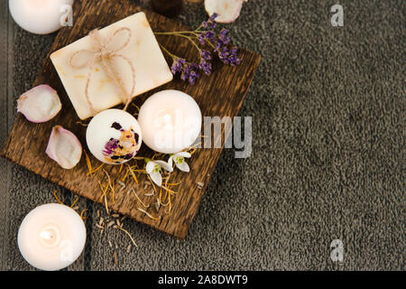 Vari prodotti da bagno relax su vassoio in legno naturale: Bomba da bagno cremosa, saponetta e bottiglie di olio aromatico. Accogliente relax a casa concetto. Foto Stock