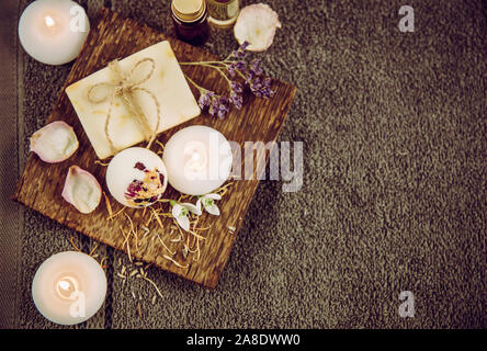 Vari prodotti da bagno relax su vassoio in legno naturale: Bomba da bagno cremosa, saponetta e bottiglie di olio aromatico. Accogliente relax a casa concetto. Foto Stock