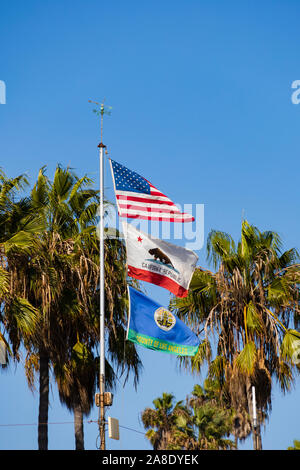 Bandiera nazionale, lo Stato di bandiera e bandiera della contea di volare insieme oltre il bagnino edificio per uffici, Santa Monica, nella contea di Los Angeles, California, Regno sta Foto Stock