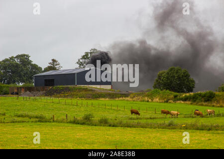 21 agosto 2019 denso fumo nero dalla combustione di pneumatici in gomma in modo irresponsabile riempiendo il cielo su una fattoria in County Fermanagh in Irlanda del Nord Foto Stock