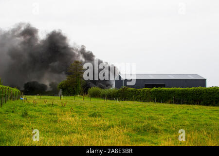 21 agosto 2019 denso fumo nero dalla combustione di pneumatici in gomma in modo irresponsabile riempiendo il cielo su una fattoria in County Fermanagh in Irlanda del Nord Foto Stock