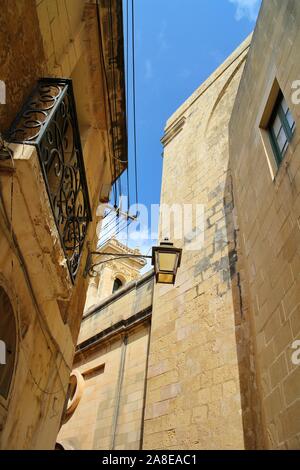 Guardando verso un lampione e metallo balcone passeggiando per le stradine di La Valletta città vecchia, Malta. Foto Stock