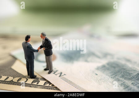 La figura imprenditore in piedi sul dollaro e yuan banconota, tenendo le mani per il successo in accordi commerciali. Concetto di guerra di trading Foto Stock