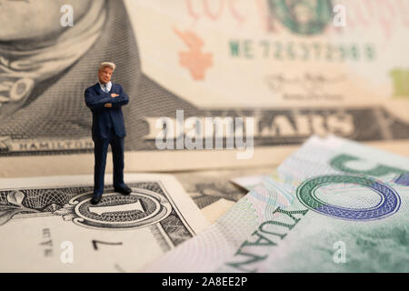 La figura imprenditore in piedi sul dollaro e yuan banconota, tenendo le mani per il successo in accordi commerciali. Concetto di guerra di trading Foto Stock