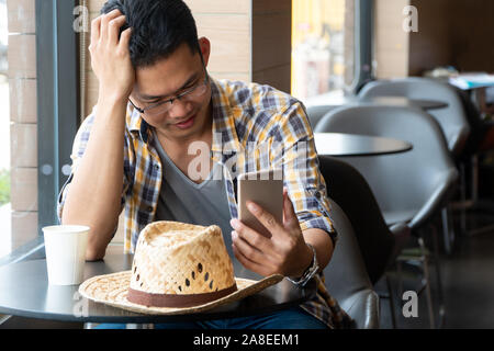 Giovani agricoltori business seduti in un ristorante e guardare gli smartphone a informazioni di apprendimento in agricoltura. Concetto di agricoltura moderna. Foto Stock