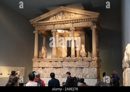 Visitatori studiare la facciata ricostruita della nereide monumento, una tomba scolpita da Xanthos in Lycia, presso il British Museum di Londra, Regno Unito Foto Stock