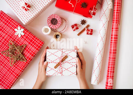 Donna con le mani un regalo di Natale scatola con decorazioni su sfondo bianco. Concetto di festa. Foto Stock