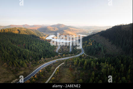 Antenna fuco vista sulle montagne di autunno con la strada di montagna serpentina, fiume e foresta. Fotografia di paesaggi Foto Stock