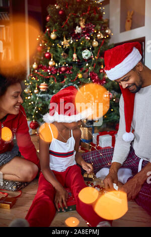 La mattina di Natale. Celebrare il Natale.carina ragazza apre un regalo per la mattina di Natale e divertirsi Foto Stock