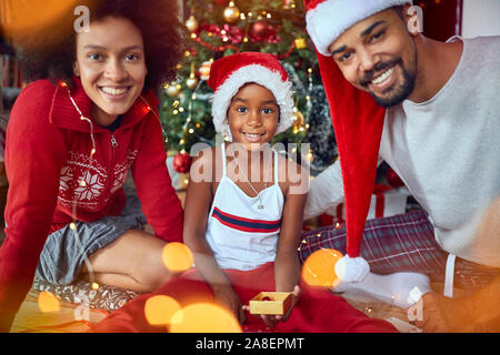 Sorridente giovane famiglia la mattina di Natale celebrando holiday Foto Stock