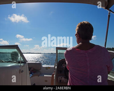 Donna al timone della barca di piacere a sud-ovest della Florida Intracoastal Waterway, Florida, Stati Uniti d'America, 30 ottobre 2019, © Katharine Andriotis Foto Stock