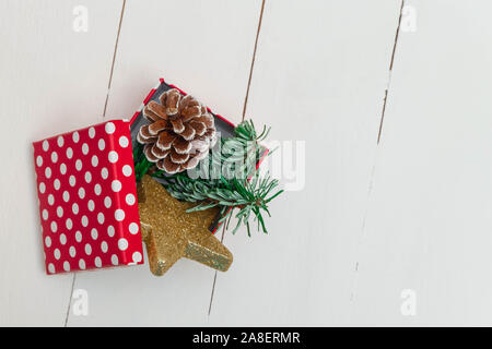 Natale composizione creativa con il riquadro rosso, golden star, Natale i rami degli alberi e il cono bianco sullo sfondo di legno. Foto Stock