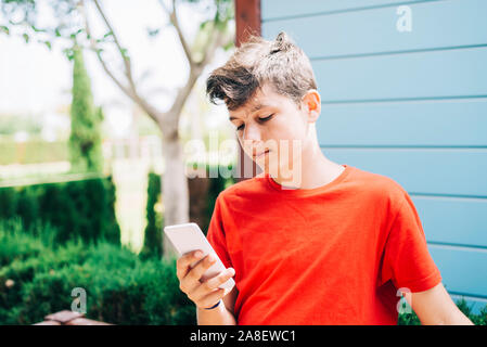 Profilo di un felice guy scrivere messaggi su un telefono intelligente Foto Stock