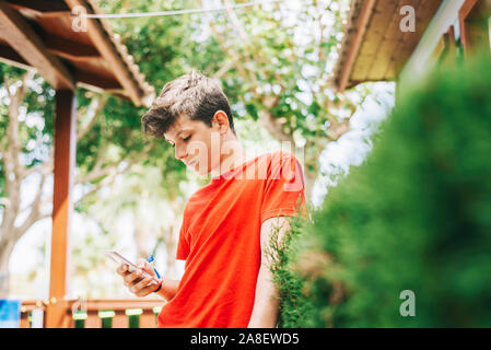 Profilo di un felice guy scrivere messaggi su un telefono intelligente Foto Stock