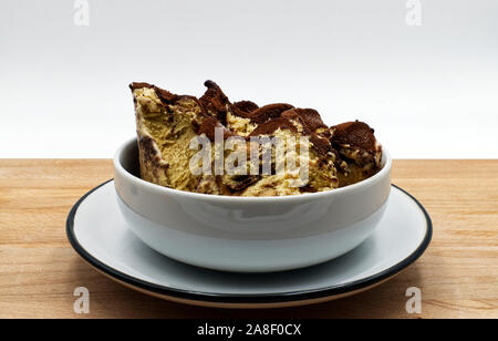 Il tiramisù gelato servito in una tazza di ceramica, tavolo in legno, isolato su bianco Foto Stock