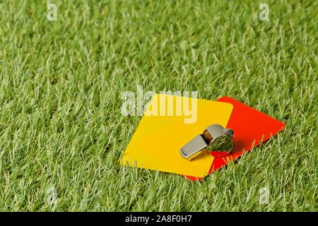 Sport calcio arbitro di colore giallo e rosso carte con fischietto cromato su sfondo di erba - pena, fallo o il concetto di sport Foto Stock