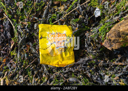 Pacchetto nitido inquinamento sulla spiaggia catturati nelle alghe marine bere sky Ocean Rescue Foto Stock