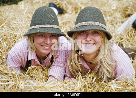 Zwei blonde Frauen, Trachtenträger, liegen fröhlich im Stroh, signor: Sì Foto Stock