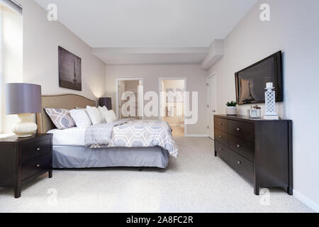 Un grande centro di appartamento con un letto di dimensione king, guardando verso un bagno e ripostiglio. Foto Stock