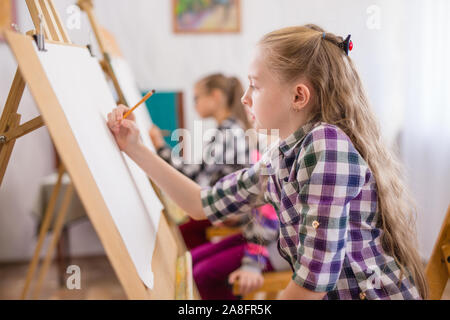 Bambini disegnare su un cavalletto alla scuola d'arte Foto Stock