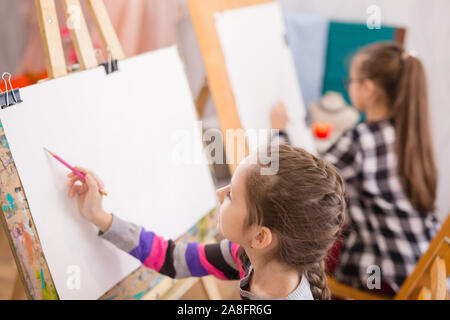 Bambini disegnare su un cavalletto alla scuola d'arte Foto Stock