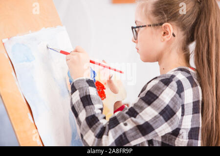 Bambini disegnare su un cavalletto alla scuola d'arte Foto Stock