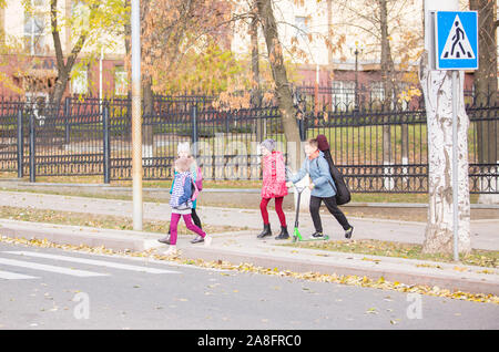 I bambini vanno a scuola il marciapiede con una società di divertimento Foto Stock