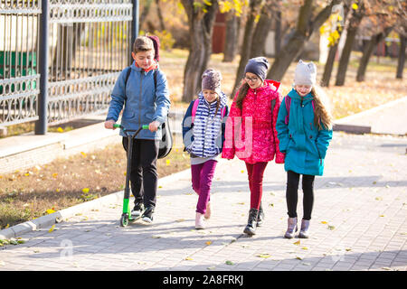 I bambini vanno a scuola il marciapiede con una società di divertimento Foto Stock