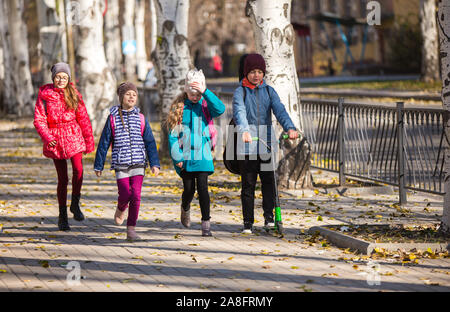 I bambini vanno a scuola il marciapiede con una società di divertimento Foto Stock